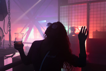 Dancing young woman silhouette at techno club