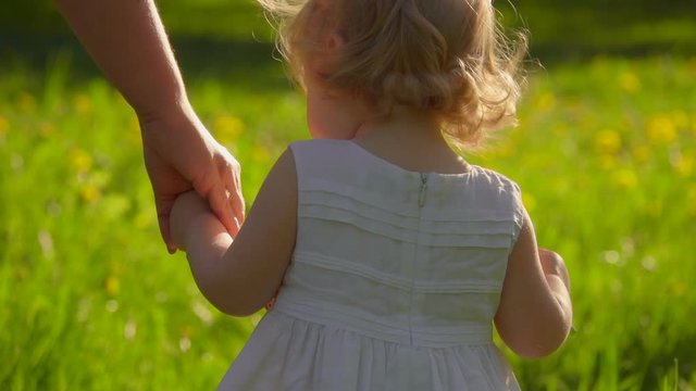 Mom and daughter holding hands and walking in the garden