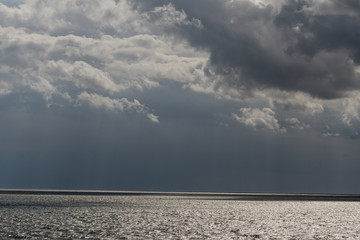 REgenwolken über gleißendem Meer