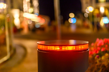 A retractable bollard with a red warning light as a barrier to a pedestrian area at night in...