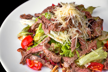 Warm salad with meat and cheese on a white plate