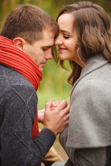 Two lovers in autumn park look on each other with love and tenderness. couple on autumn walk outdoors. Gentle hugs