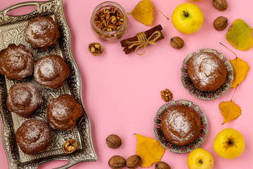 Homemade muffins with apples and nuts arranged on a tray on a pink background, top view, horizontal orientation, closeup