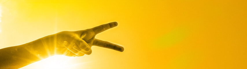 Hände formen Victory-Zeichen - Hintergrund gelber Himmel mit Sonne