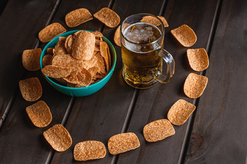 Set of heart shaped french fries on the wooden table with glass of beer background