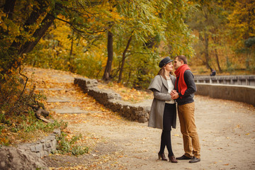 Obraz premium Couple weared in autumn-style clothes (oranfe scarf and vest) running through the autumn landscape. Alley covered with yellow foliage. Autumn walk outdoors. Two lovers in autumn park. Romantic dating