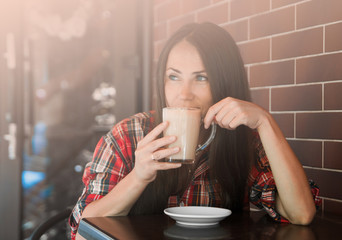 Beautiful woman with long hair drinks coffee outdoors.