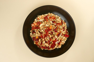 A tasty salt granola with pepper in black bowl on baige bakground.