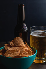 Set of french fries on the wooden table with glass of beer and black background