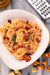 pasta with organic chanterelles. portion of spaghetti pasta with fried chanterelles in a creamy garlic sauce with cheese on a table