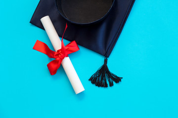 Top view of graduation mortarboard and diploma isolated on blue background, education concept