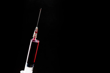 syringe filled with blood on a black background	