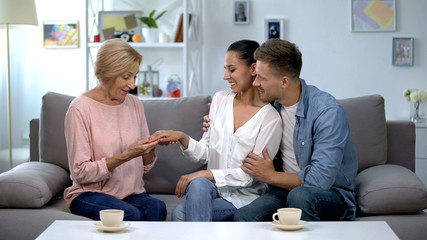 Couple showing engagement ring to mother, trustful family relationship, marriage