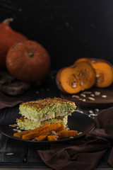 Zucchini pie with baked pumpkin on dark wooden background close-up with copy space.