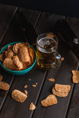 Set of french fries on the wooden table with glass of beer and black background