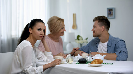 Obraz na płótnie Canvas Mother-in-law and son talking and ignoring girlfriend, unhealthy relations