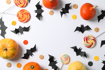 Candy, decorative bats and pumpkins on white background, space for text