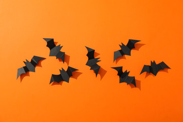 Flat lay with decorative bats on orange background, copy space