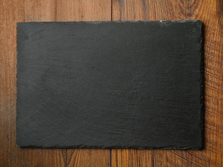 Clean slate plate on a wooden table surface, Top view. Copy space.