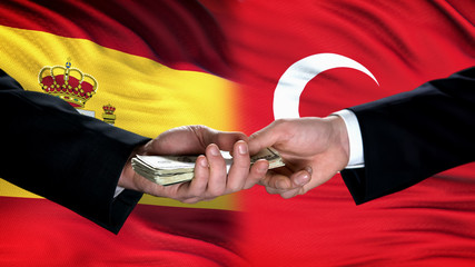 Spain and Turkey officials exchanging money, flag background, cooperation