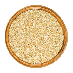 White quinoa in wooden bowl. Raw dried seeds of Chenopodium quinoa, a gluten-free pseudocereal, originated in the Andean region. Closeup, from above, on white background, isolated macro food photo.