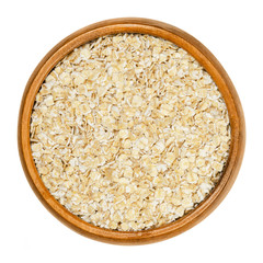 Small-leaved oatmeal, rolled white oats in wooden bowl. Dehusked hulled oats, rolled into flakes, for porridge, granola or muesli. Closeup, from above, on white background, isolated macro food photo.