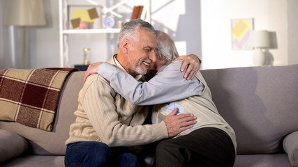 Senior male friends laughing and hugging at home, true old friendship, rest