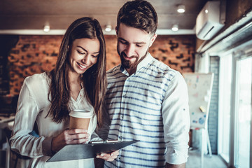 Handsome businessman and beautiful business lady reviewing documents in office