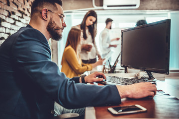 Young man sitting in office and working on desktop pc.