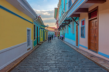 People walking by the colonial style architecture in the most beautiful cobblestone street of...