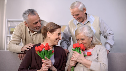 Happy old women sniffing red tulips, romantic present from aged husband, holiday