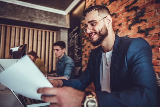 Young Finance Market Analyst Working On Laptop, Analyzing Documents In Office