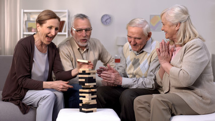 Active elderly people playing block game, spending time in friendly atmosphere