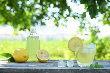 Glasses of lemon juice on a wooden table, summer set, outdoor greed blured background,boke.Water...