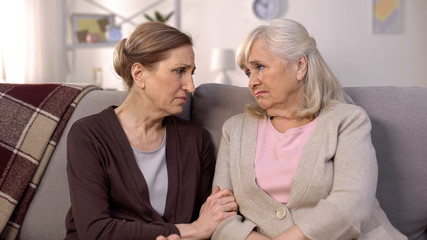 Mature friends supporting and comforting each other sitting on sofa pain of loss
