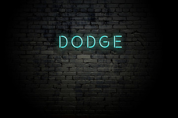 Highlighted brick wall with neon inscription dodge