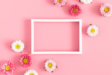 Beautiful flowers composition. White photo frame, pink flowers on pastel pink background. Valentines Day, Happy Women's Day, Mother's day. Flat lay, top view, copy space