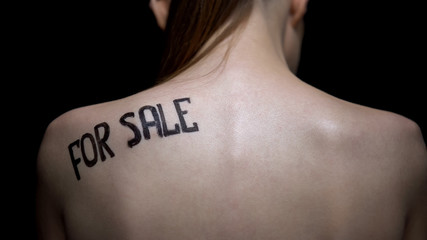 Insecure naked girl showing for sale phrase on shoulder, illegal sex industry