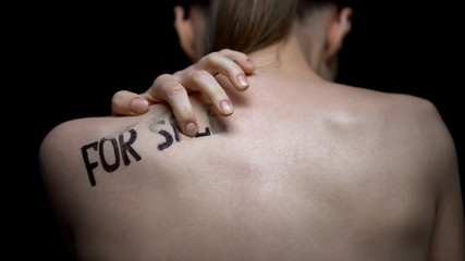 Frightened naked woman wiping for sale phrase from shoulder, human trafficking
