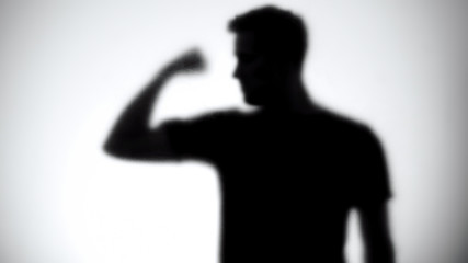 Silhouette of confident man showing biceps, bodybuilding and fitness, close-up
