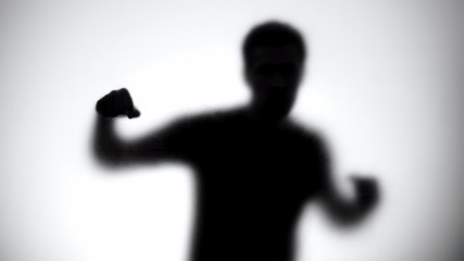 Silhouette of man behind glass attacking enemy, anonymous fight club, athlete