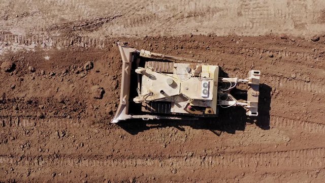 Bulldozer pushing large amount of fresh soil, Aerial follow footage.