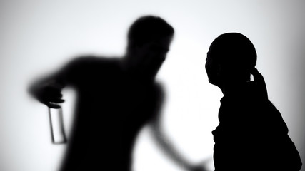 Silhouette of wife and husband quarreling, man holding alcohol bottle, addiction