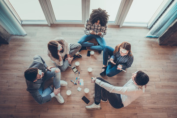 Five employees sitting on the floor with legs crossed and doing brainstorming.