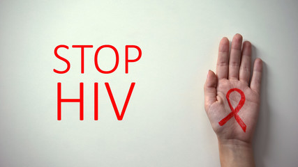 Stop HIV inscription, hand with red ribbon, awareness and prevention campaign