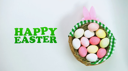 Happy Easter inscription, basket with colored eggs on lying on table, holiday