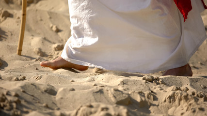 Fototapeta na wymiar Prophet legs walking on sand, following of Jesus faith, religious conversion