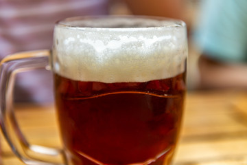 Man is holding a freshly tapped glass of beer in his hand
