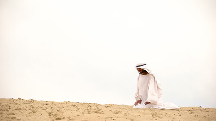 Tired Bedouin kneeling in desert, exhausted and lost, overcoming difficulties