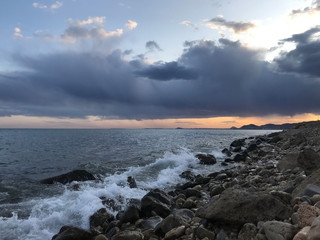 Dramatic storm photo of a coastline stone beach in sunset